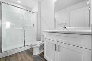 Full bathroom featuring vanity, a shower stall, dark wood-style floors, and recessed lighting