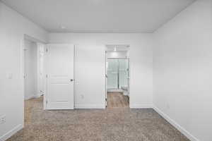 Unfurnished bedroom with light carpet and ensuite bath