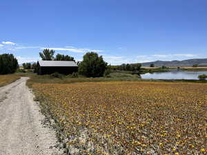 View of dirt / gravel road with a water and mountain view and a rural view