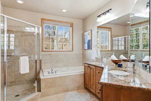 Full bathroom featuring double vanity, a shower stall, a bath, recessed lighting, and light tile patterned floors