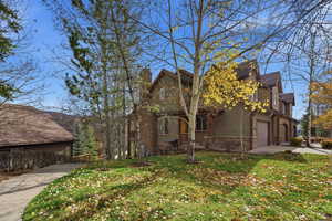 View of property exterior featuring a lawn, driveway, a garage, and a chimney