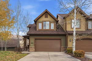 Craftsman house with stone siding, roof with shingles, an attached garage, and concrete driveway