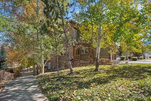 View of front of home featuring stone siding, a front lawn, and driveway