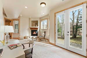 Doorway featuring a glass covered fireplace, recessed lighting, carpet flooring, and french doors