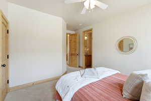 Carpeted bedroom featuring ceiling fan and connected bathroom