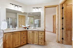 Bathroom with double vanity, a stall shower, and light carpet