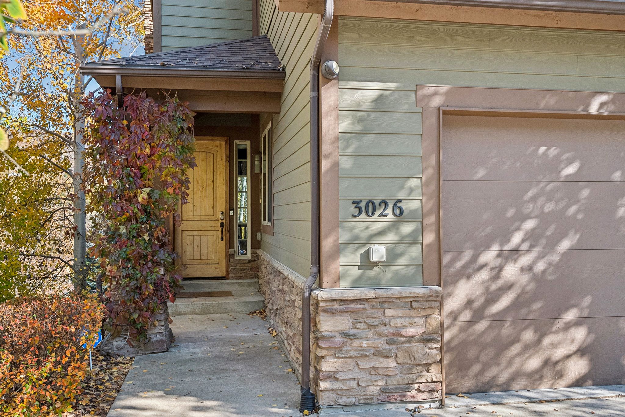 Property entrance featuring a garage, stone siding, and a shingled roof