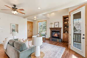 Living room featuring ceiling fan, a tiled fireplace, wood finished floors, and recessed lighting