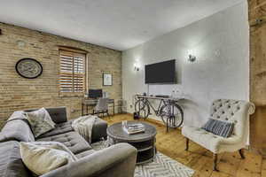 Living area featuring brick wall, a desk, hardwood / wood-style floors