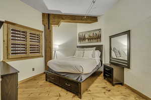 Bedroom featuring light wood-style flooring, and beam ceiling