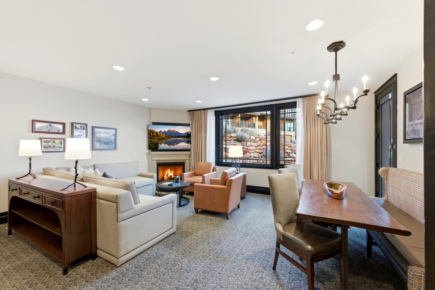 Carpeted living room featuring a lit fireplace, a chandelier, and recessed lighting