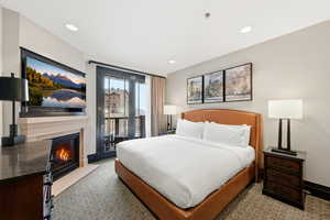 Bedroom featuring access to exterior, a fireplace with flush hearth, and carpet