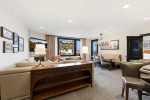 Living area featuring a chandelier, light colored carpet, and recessed lighting