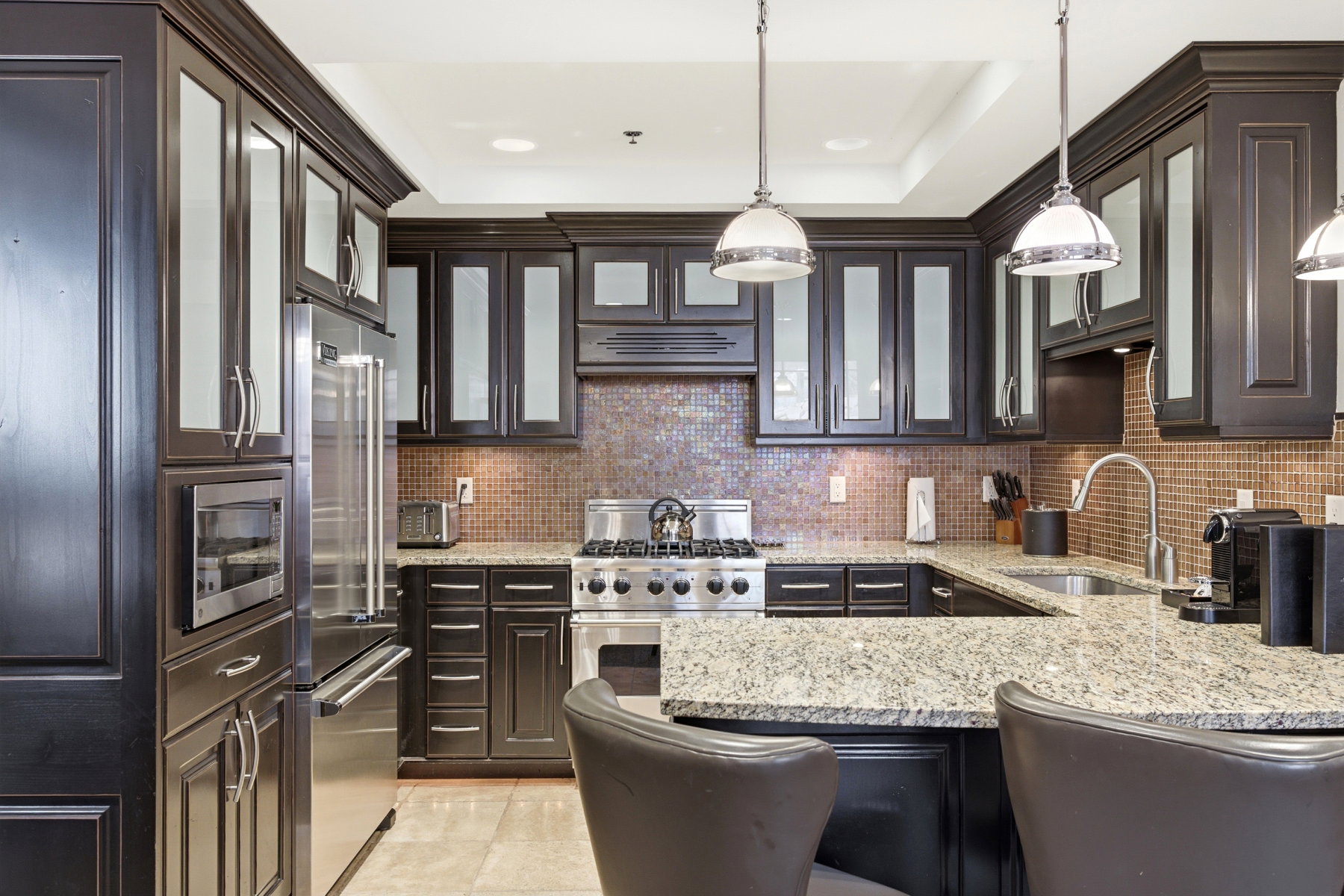 Kitchen with glass insert cabinets, light stone countertops, high quality appliances, and decorative backsplash