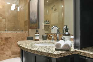 Full bathroom with vanity, a tile shower, and tasteful backsplash