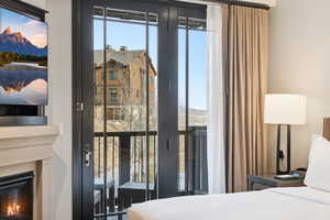 Bedroom featuring multiple windows, a mountain view, and a glass covered fireplace