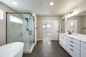 Full bath featuring double vanity, a freestanding tub, a marble finish shower, and recessed lighting