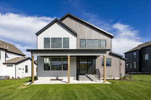 Rear view of house with a lawn and a patio