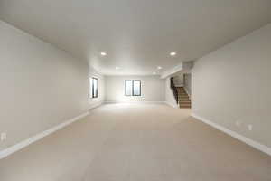 Below grade area with recessed lighting, stairs, and light colored carpet