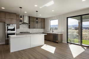 Kitchen featuring tasteful backsplash, modern cabinets, stainless steel appliances, wall chimney exhaust hood, and recessed lighting