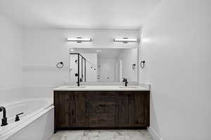 Full bathroom with double vanity, a garden tub, light marble finish floors, a stall shower, and a textured ceiling