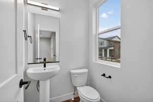 Half bathroom with toilet and wood finished floors