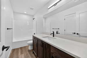 Bathroom featuring bathing tub / shower combination, vanity, and dark wood-type flooring