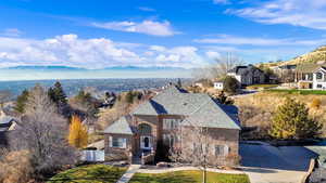 French provincial home featuring a valley view, brick siding, a residential view, and a front lawn