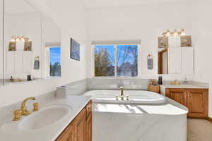 Full bath featuring a bath and two vanities