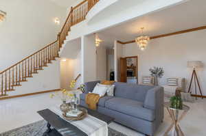 Living room with a chandelier, stairs, and a high ceiling