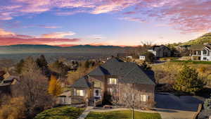 View of front of home featuring roof with shingles, a valley view, concrete driveway, a yard, and brick siding