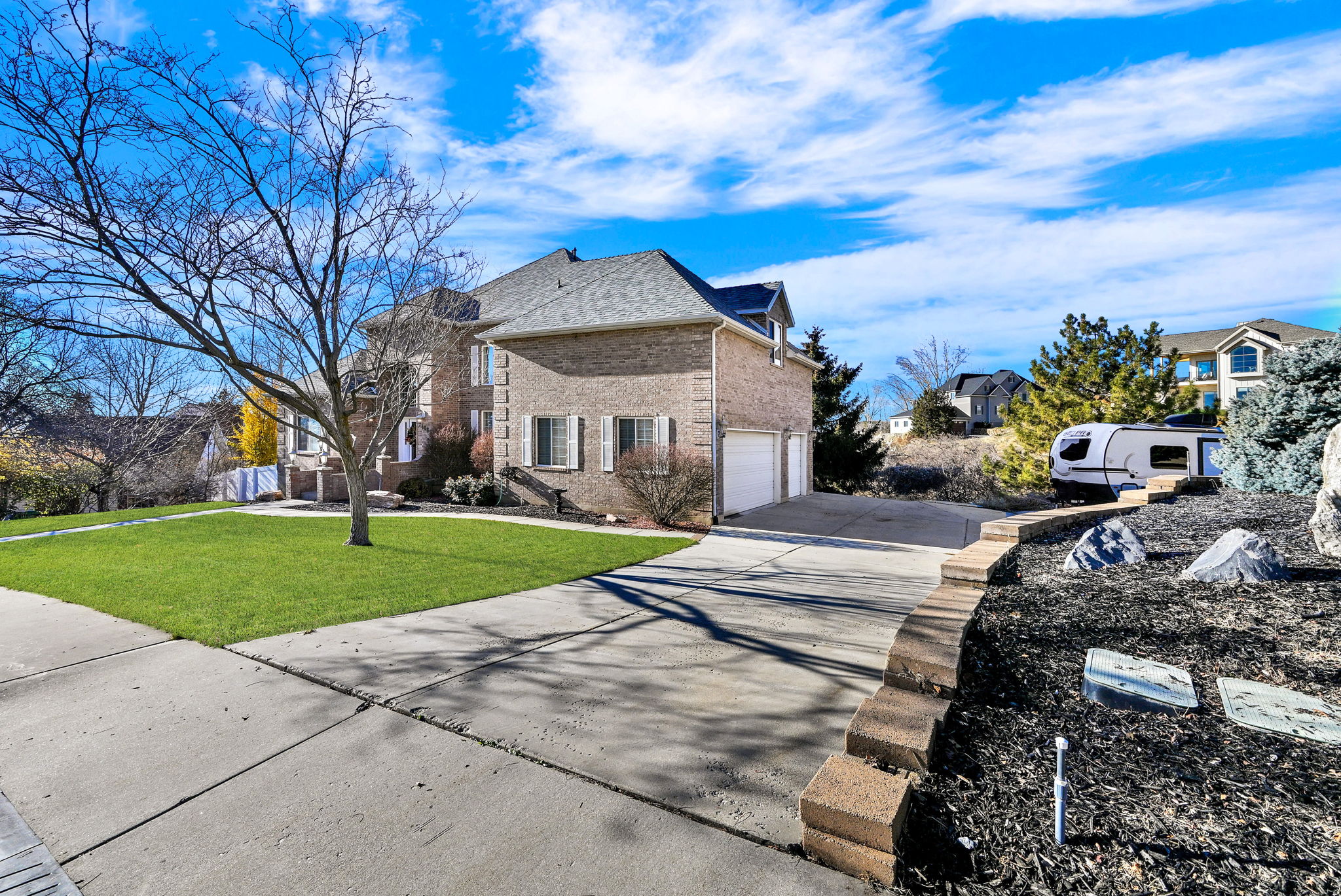 View of side of property featuring concrete driveway, brick siding, a lawn, a residential view, and an attached garage