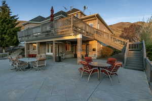 Back of property featuring stairway, outdoor dining space, a patio area, and a deck