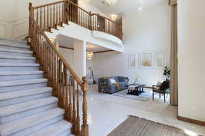 Stairs with a chandelier, a towering ceiling, and tile patterned floors