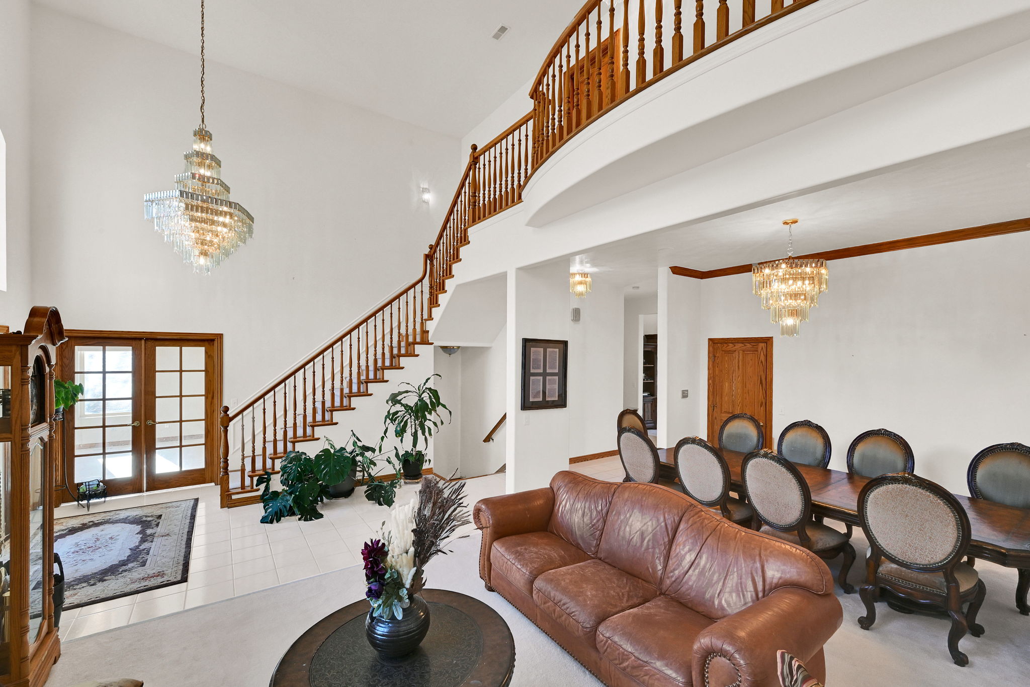 Living room with a chandelier, a high ceiling, french doors, and stairway