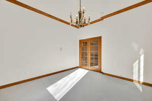 Carpeted empty room with a chandelier and ornamental molding