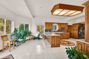 Kitchen featuring brown cabinetry, backsplash, a kitchen breakfast bar, a peninsula, and refrigerator with ice dispenser