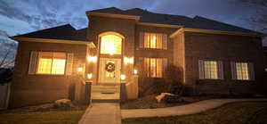 View of front of property featuring brick siding and roof with shingles