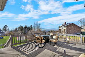 Deck featuring a mountain view, outdoor dining area, and a yard