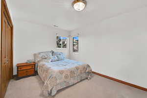 Carpeted bedroom featuring a closet and baseboards