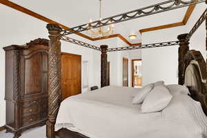 Carpeted bedroom featuring connected bathroom, crown molding, and a chandelier