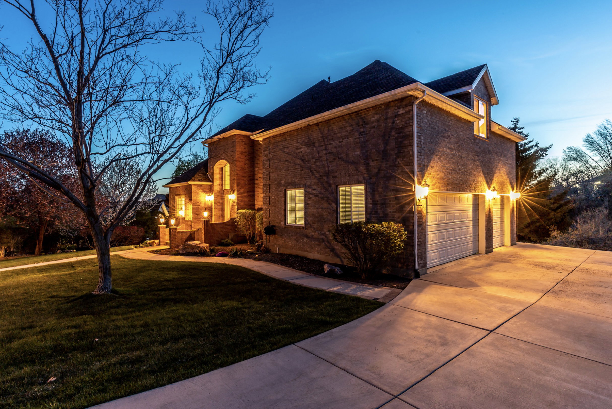 View of property exterior with a yard, a garage, concrete driveway, and brick siding
