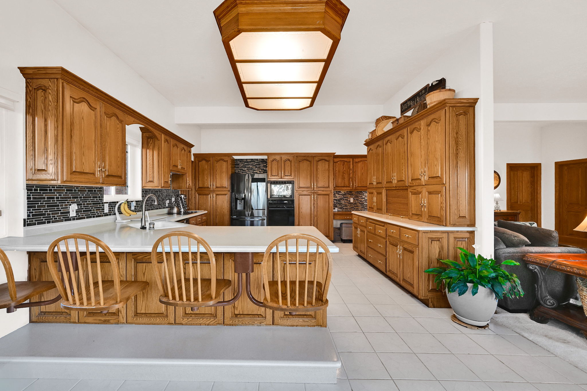 Kitchen with brown cabinetry, light countertops, a peninsula, and backsplash