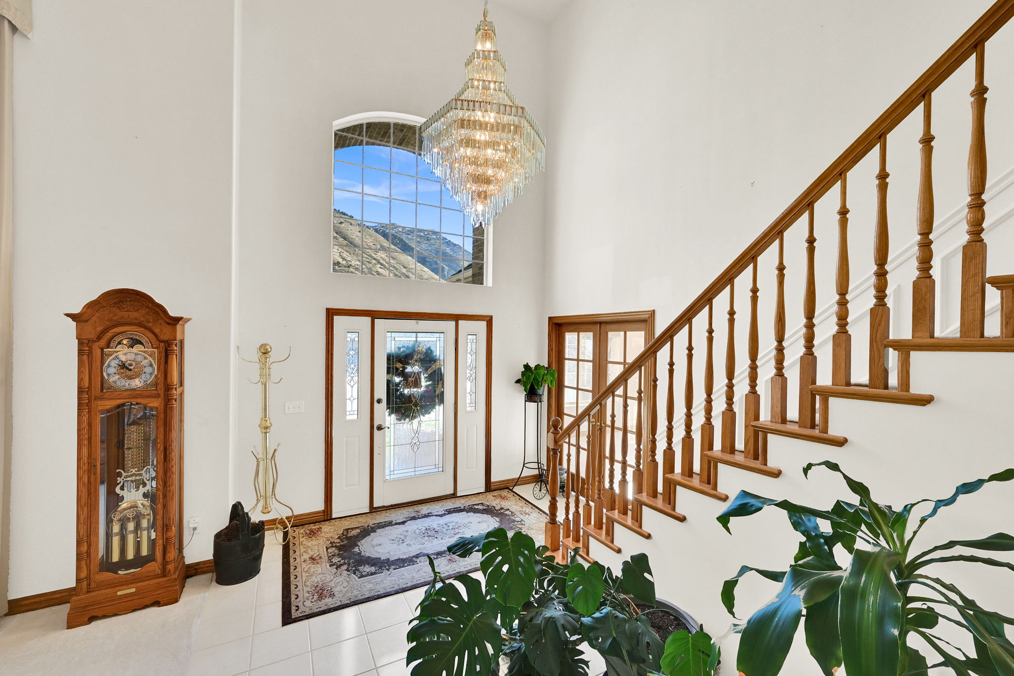 Foyer featuring a towering ceiling, stairs, tile patterned flooring, and a chandelier