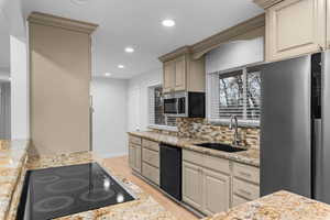 Kitchen featuring black appliances, light stone counters, recessed lighting, light wood-style floors, and tasteful backsplash