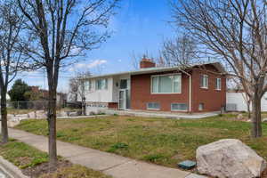 Bi-level home with a chimney, brick siding, and a porch
