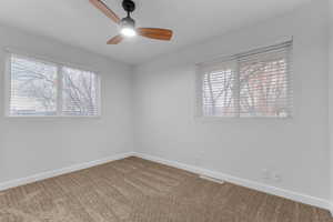 Carpeted empty room featuring ceiling fan and plenty of natural light
