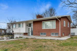 View of front of house featuring a chimney, brick siding, and a garage