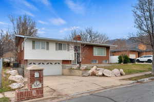 View of front of house featuring concrete driveway, a chimney, and an attached garage