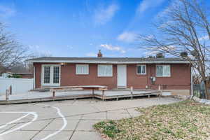 Rear view of property featuring a chimney, a wooden deck, brick siding, and french doors